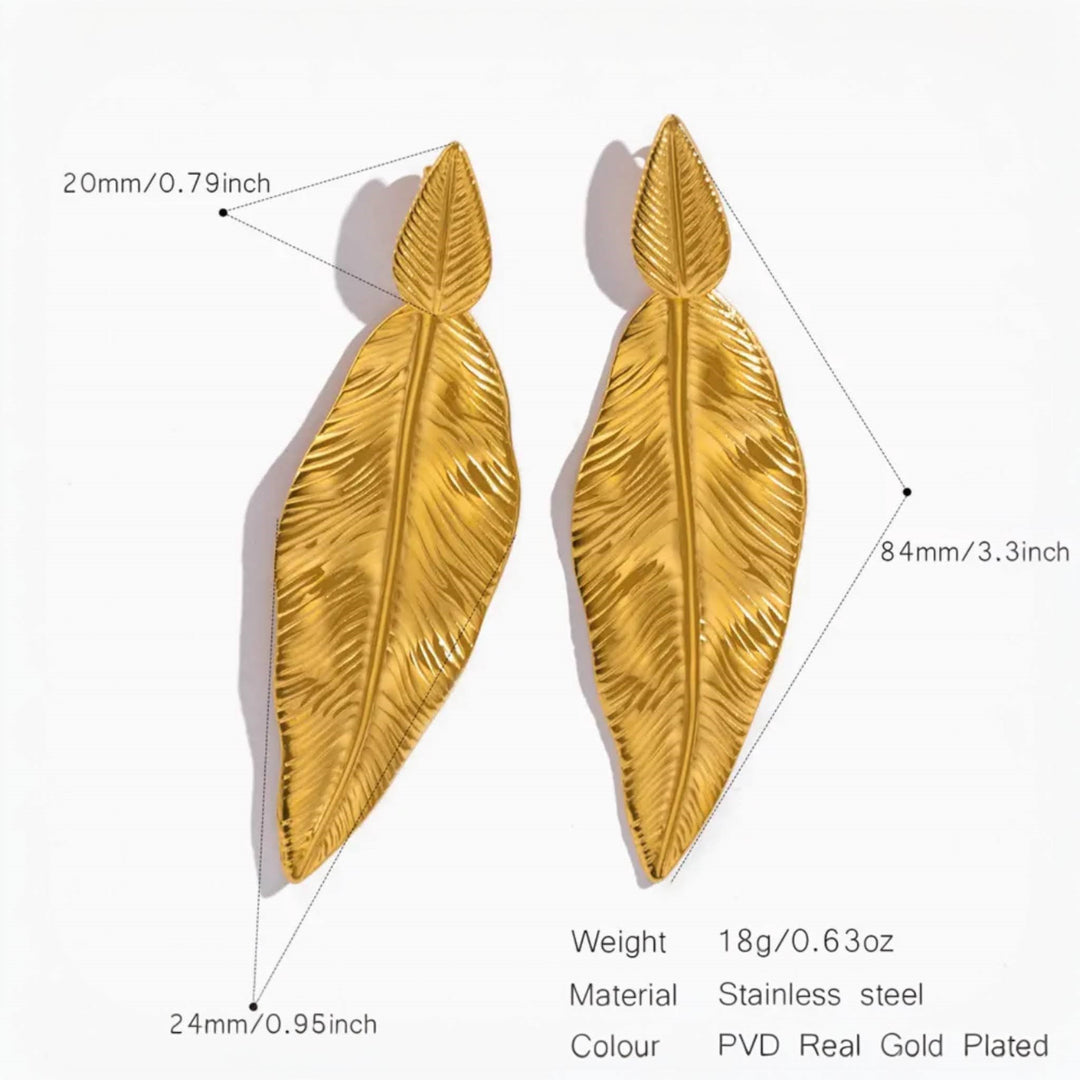 Pair of gold leaf-shaped earrings with intricate detailing, made of stainless steel and PVD real 18K gold plated. Dimensions: 84mm x 24mm.