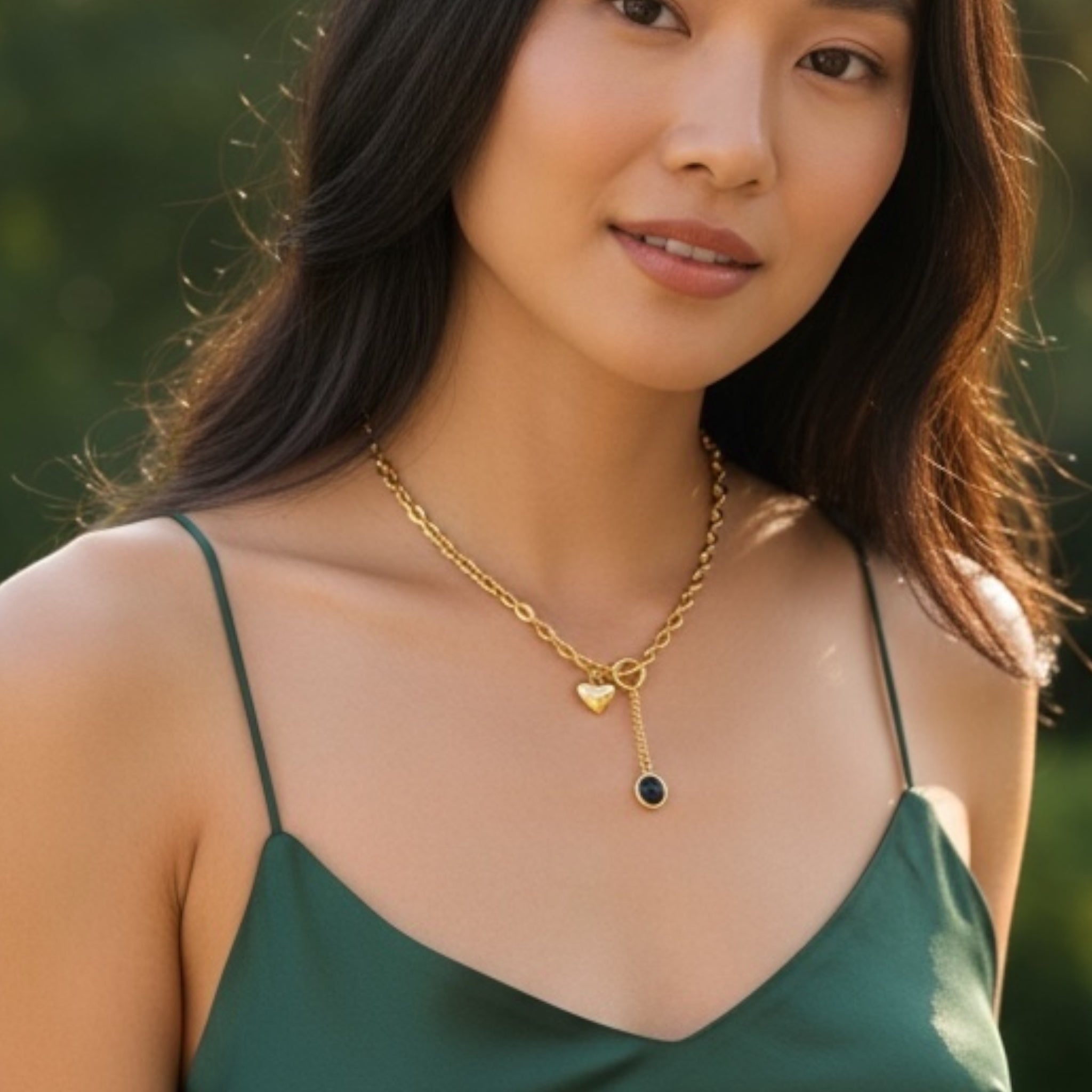 Woman wearing a gold necklace with heart and key pendants outdoors