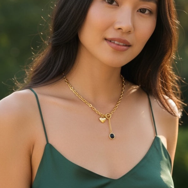 Woman wearing a gold necklace with heart and key pendants outdoors